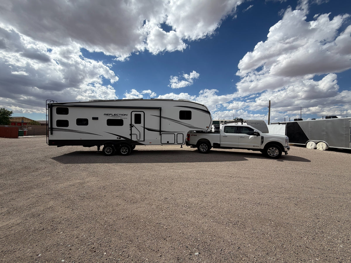 Fifth-wheel RV and pickup beneath a dramatic sky