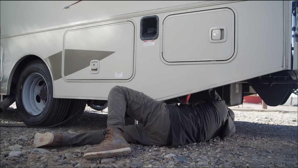 Jordan working beneath an RV during a mobile service visit